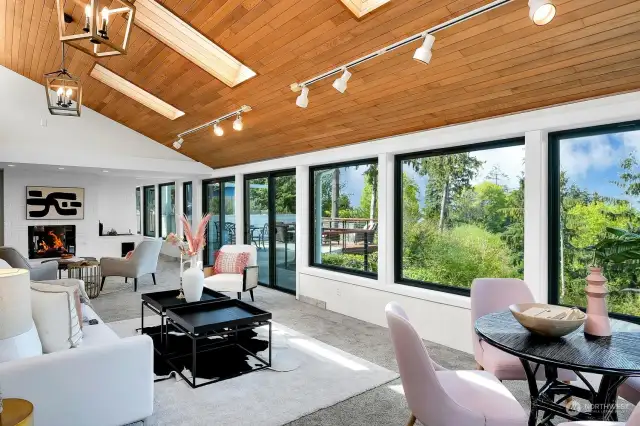 The living room has two slider doors for access to the deck, patio and pond on the lower level! A wonderful mix of textures combine wood, stone and glass in this open concept room featuring skylights, gas fireplace, and brick accent wall.