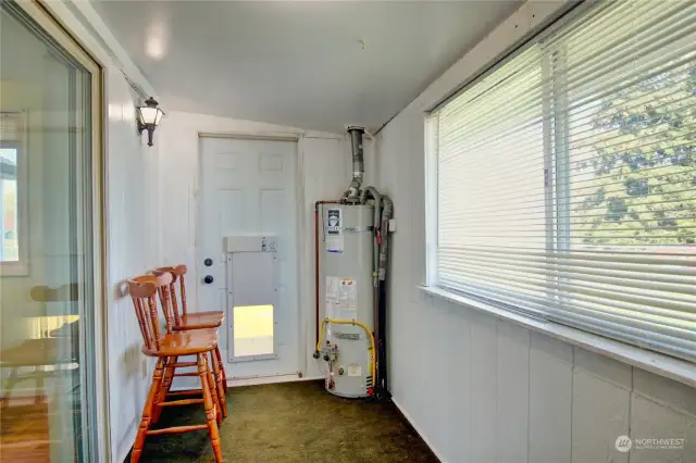Enclosed back porch with gas hot water heater off of kitchen.