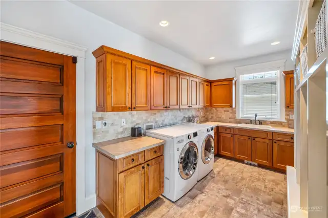 Laundry room with tile floors, lots of cabinets plus a large sink, just inside the garage door.