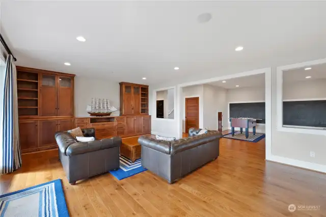 Lower level family room with built-in storage, display shelves, and gorgeous wood floors.