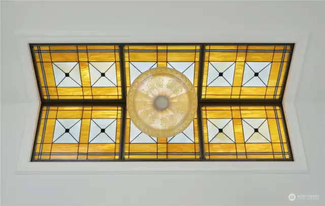 The custom window shown was meticulously and artfully crafted. Using a combination of kiln-fired art glass and etched glass in hand-picked colors, this stunning embodiment of period styling perfectly showcases the antique Czech glass pendant light fixture.