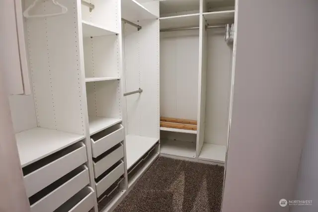 Primary bedroom boasts a large walk in closet featuring custom closet organizer