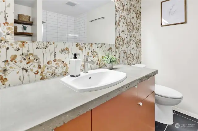 Primary bath features concrete counters, tiled floors, and a tiled shower