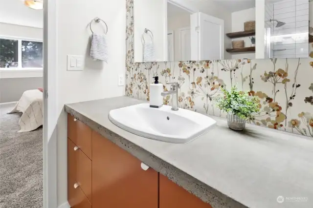 Primary bath features concrete counters, tiled floors, and a tiled shower.