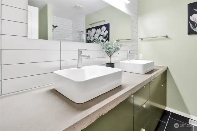 Guest bath features concrete counters, filed floor, and tiled shower.
