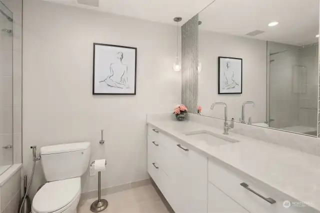 Lower level bathroom, quartz counters and glass surround shower with seating.