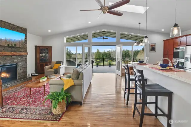 The large great room is the center of the home, with gleaming hardwood floors, vaulted ceiling, custom skylights, and French doors opening to the oversized covered deck.
