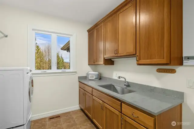 Laundry Room located on main floor with slab-granitite countertop and stainless-steel work sink (2024) with overhead cabinets. 2 additional closets with California Closets systems great for organizing.