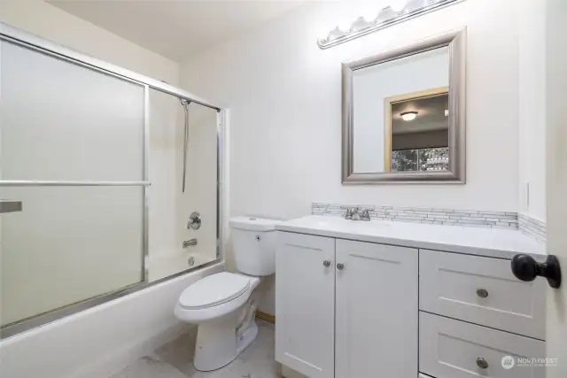 Refreshed primary bath features all-new vinyl plank flooring, vanity, toilet and paint.