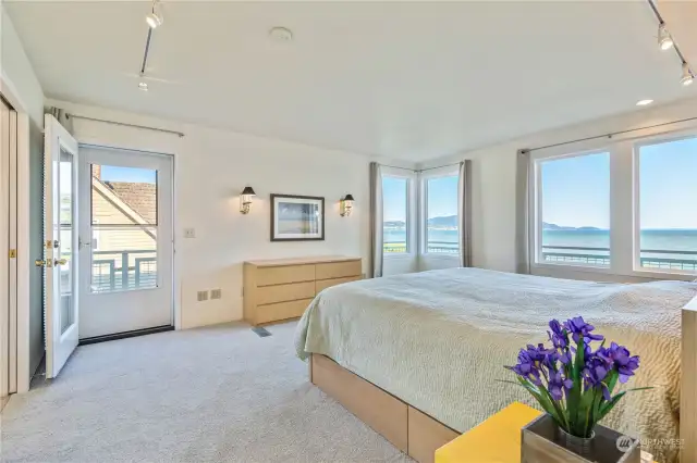 The spacious primary bedroom has stunning views and access to the full wrap-around deck.