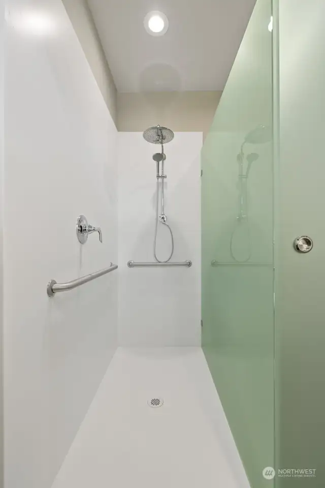 Grohe rain shower plus handheld in this barrier-free all-Corian shower. Unique glass barn door shutters shower or toilet compartment