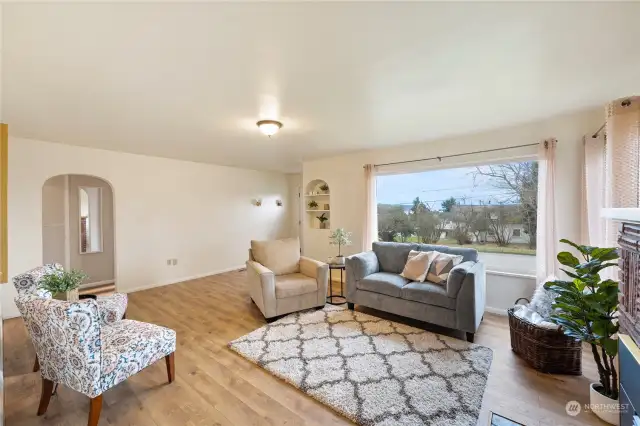 Living room with mid-century features, rounded archways, built in shelf. LVP flooring and gas fireplace insert for cozy winter days. Large picture window will boast views of majestic Mt. Baker and peekaboo water views.
