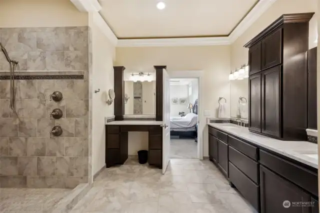 En-suite primary bathroom with heated ceramic tile floors, dual head walk- in shower, lots of cabinet space, quartz countertops, coffered ceiling with rope lighting, double sinks plus a separate makeup vanity area.
