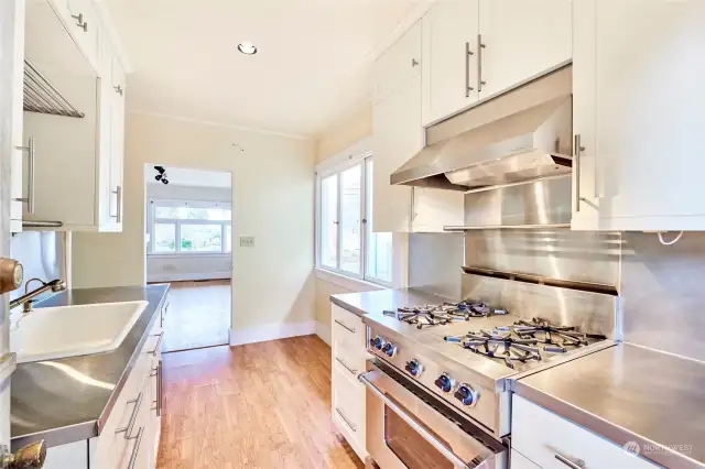 Chef-grade kitchen with stout gas stove and low-maintenance stainless counters and backsplash.