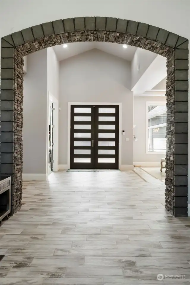This stunning foyer has soaring cathedral ceilings,beautiful custom tile that looks like wood flooring! Stone accent wall welcomes you into the formal living area.