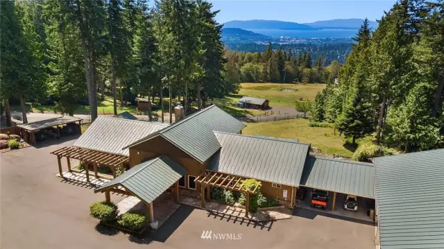 Current primary home, built with wood milled from the land, boasts main level living, custom details throughout, gourmet Kitchen, covered outdoor living space, oversized garage & shop with business office.