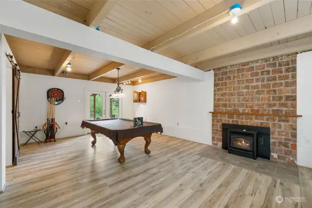 Family room w/wood lined-beamed ceiling. The LVP flooring continues in this space along with a pellet stove insert. French doors lead to the back patio. Pool table w/cues & balls convey.