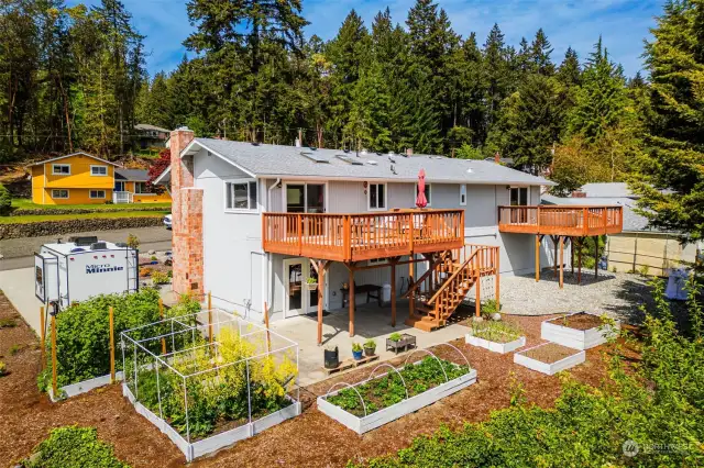 Delightful gardens and low maintenance landscaping for an outdoor oasis of enjoyment. Private Primary Bedroom deck to the right. Main deck is off dining area and offers stairs down to lower patio and backyard access.