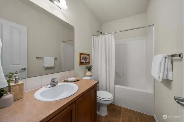 The full hallway bathroom features a single vanity, offering plenty of counter & storage space, and a shower-tub combo, providing versatility and functionality for everyday use.