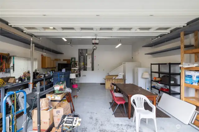 Generously sized garage with built-in workbench, shelfing, and cabinets
