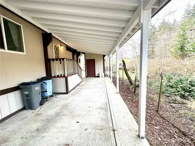 Covered carport parking with side entry to home, and storage shed in the background