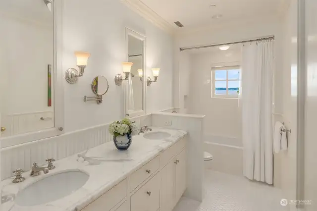 Every element comes together harmoniously in this crisp, fresh bathroom with its gorgeous marble counter top, bead board and antique inspired faucets and fixtures.