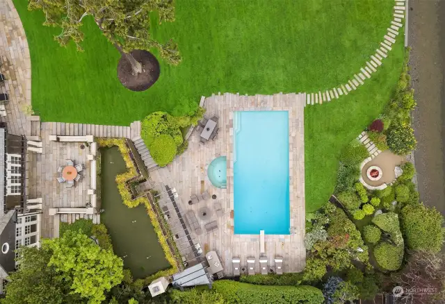 An aerial view of the pool, putting green, lakeside firepit and the sandy beach access beyond. Designed and installed by notable stone artist, Richard Rhodes sculpted all of the hardscapes. The pool deck and all patios and walkways on the property are antique granite pavers salvaged from the ancient center of Guangzhou, China.