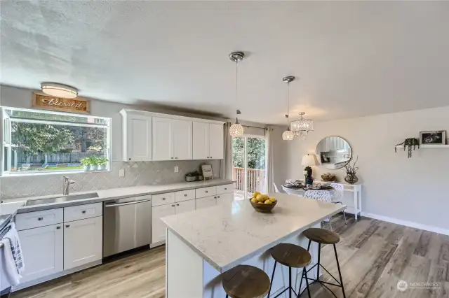 Open Kitchen with Bright White Cabinets, Stainless Steel Appliances, Enchanted Greenhouse Kitchen Window. Definitely Room for those Parties and Celebrations!