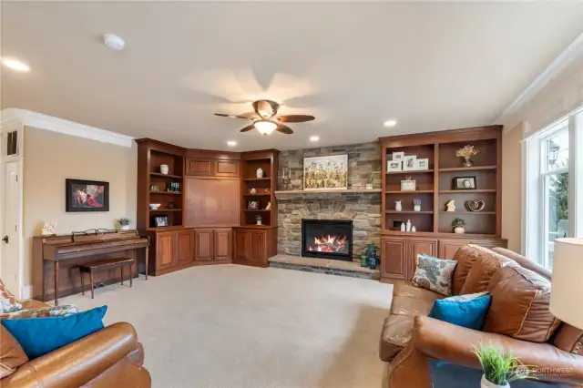 Built-in cabinets and bookcases surround the gas stone fireplace.