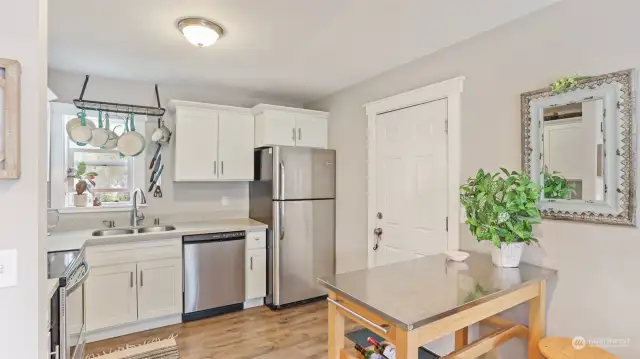 Kitchen offers newer white shaker cabinets, quartz counters, all SS appliances & a hanging pot rack.