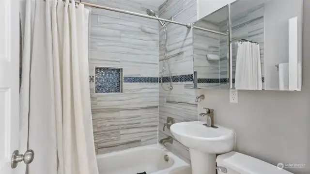 Bathroom features beautiful tile surround shower/tub combo with wall niche.