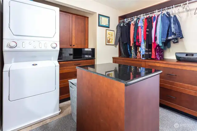 Large walk-in closet with custom cabinets, stackable washer and dryer