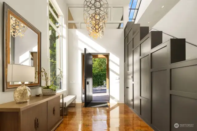 Sunlit foyer welcomes you home with custom 9 ft pivot door and beautiful Mauresque chandelier.