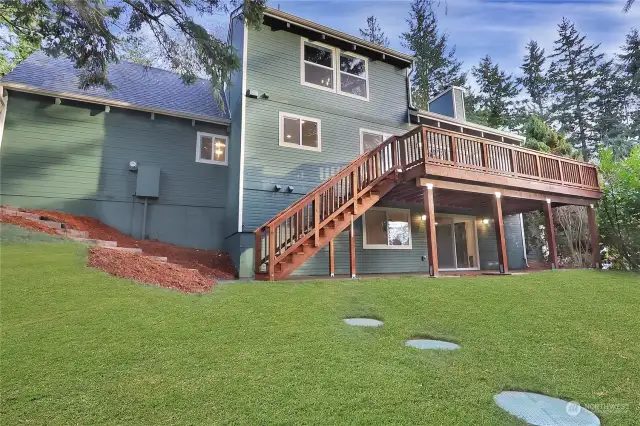 View of the Back of the home. Notice the Daylight Basement. Brand-New Deck is an impressive 27x10 with stairs to back yard & patio and new sod and bark too! Septic on Riser and TOS complete.