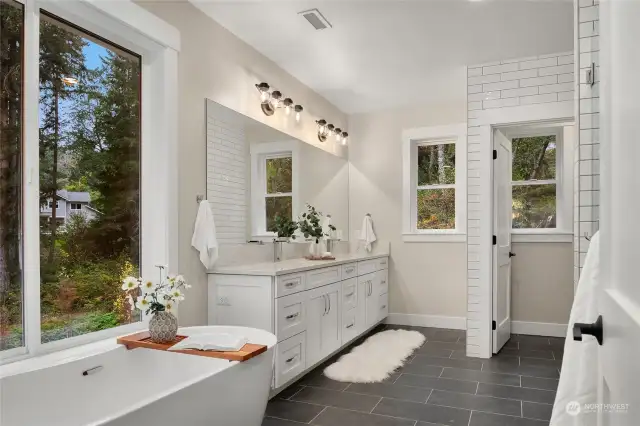 Slipper tub with lovely view through  oversized window. Quartz vanity with mirror  and loads of light make the morning routine  a delight. Water closet adds a nice element  of privacy.