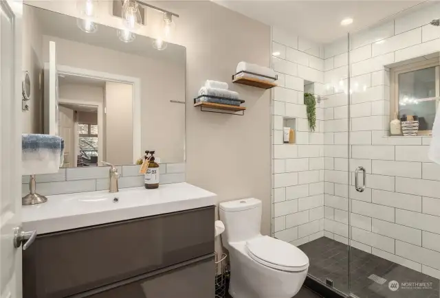 Three-quarter bath with large shower and heated flooring. The laundry room is located in between the bathroom and the bedroom.