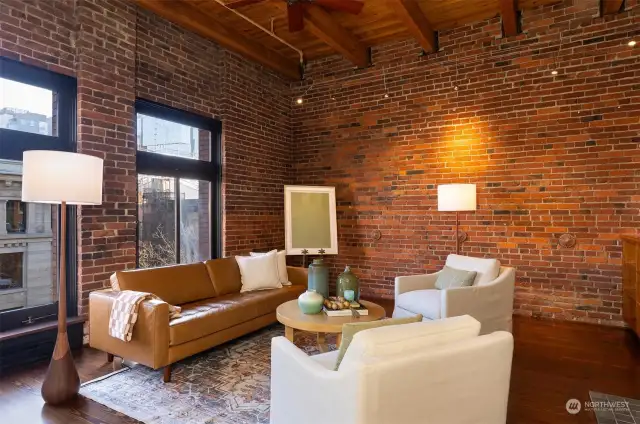 Spacious & light filled living room with exposed beams and wall of bricks.
