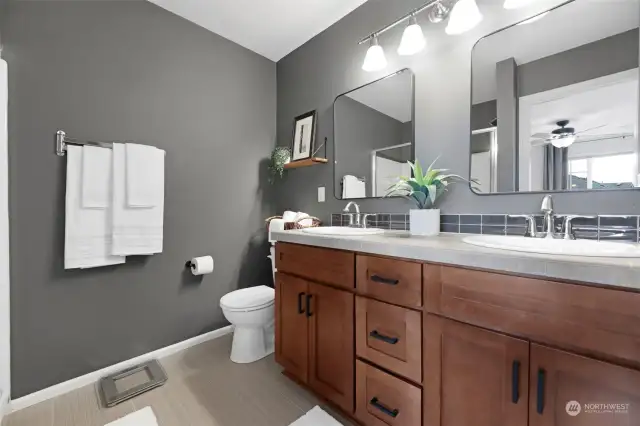 Primary ensuite bathroom with custom paint, builder upgraded tile flooring and counters + seller upgraded hardware, mirrors and shelving