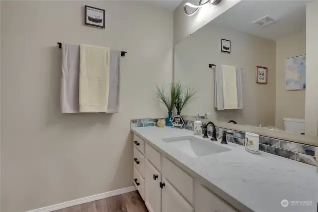 Primary Bath w/White Cabinets, Laminate Floors, Quartz Counters, Tile Backsplash.