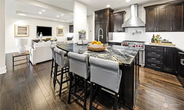 The kitchen features a gorgeous slab soapstone island/eating bar, slab quartz countertops, stainless steel appliances, and contrasting espresso-stained cabinetry.