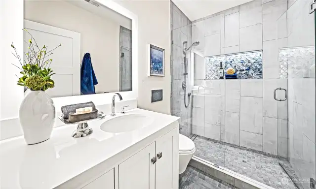 The guest suite has a remodeled en suite bath with a custom vanity, electric mirror, timed fan, and wall-hung toilet.