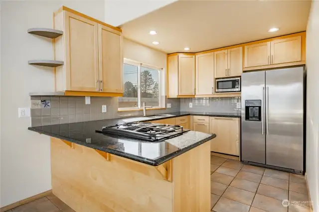 Remodeled kitchen with maple cabinets, granite counters, stainless appliances, and new tile backsplash. Notice the dishwasher with matching cabinetry front.