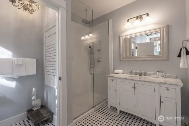 Complete with a custom vanity with marble top, oversized shower, vintage tile, and claw foot tub.