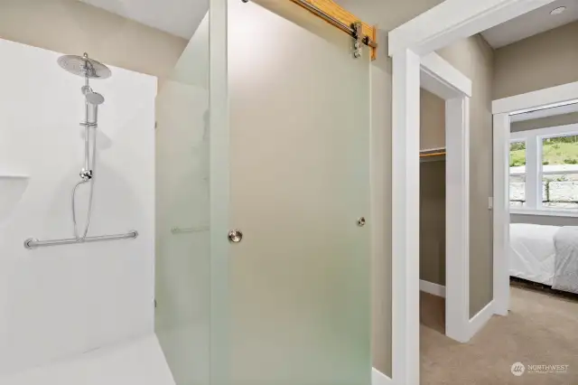 Unique glass barn door is cleverly used to close the toilet or the 6' deep roll-in Corian shower. Note the beam above and Grohe rain shower. Plus handheld and grab bars.