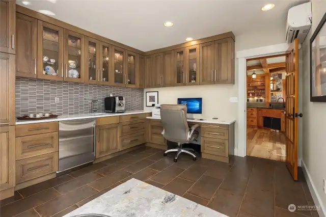 Conveniently located off the kitchen is a versatile room with glass tile backsplash, a Sub Zero bar fridge and custom wood cabinets. Perfect as a home office and/or morning room.