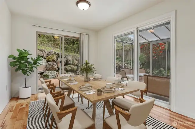 Formal dining room with hardwood floors has sliding door to back deck and an attached sun room.  Opens to living room.  Virtually staged photo.