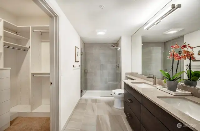 Luxurious primary bath with dual sinks and an attached walk-in closet with built-in custom organization.