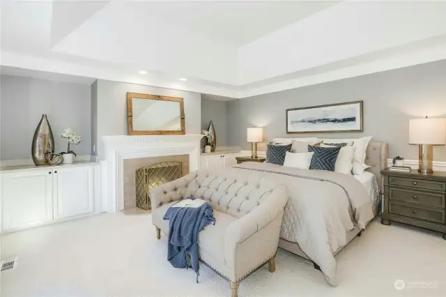 The luxurious upper level primary suite features a fireplace, custom built-ins, a coved ceiling, wainscoting and crown molding.