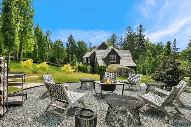 Multiple outdoor living spaces include a fire pit, meandering paths that connect to an enchanted wooded area with swings, a games lawn for cricket or soccer, a terraced lounging area and a meadow like lawn.