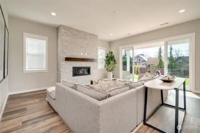 Great room with electric fireplace and wall of glass nesting slider doors to spacious covered patio/deck with pine soffit and recessed lighting.
